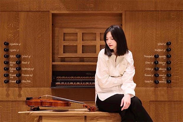 violist Chanlian Chen sitting in front of organ