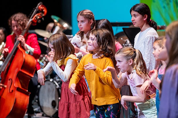 Children pretending to be animals with orchestra