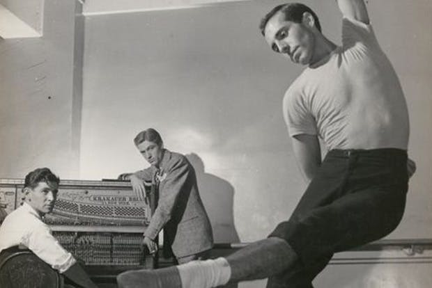 Leonard Bernstein and another man sitting at a piano observing a ballet dancer