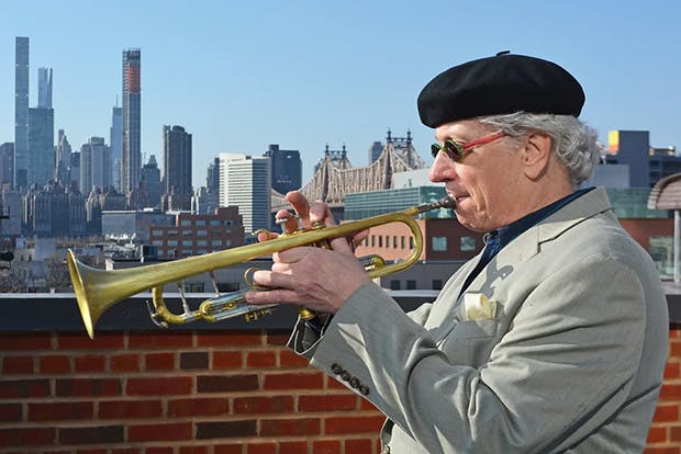 Tim Hagans in profile on trumpet against New York skyline