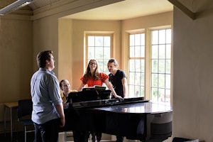 Acting students around piano