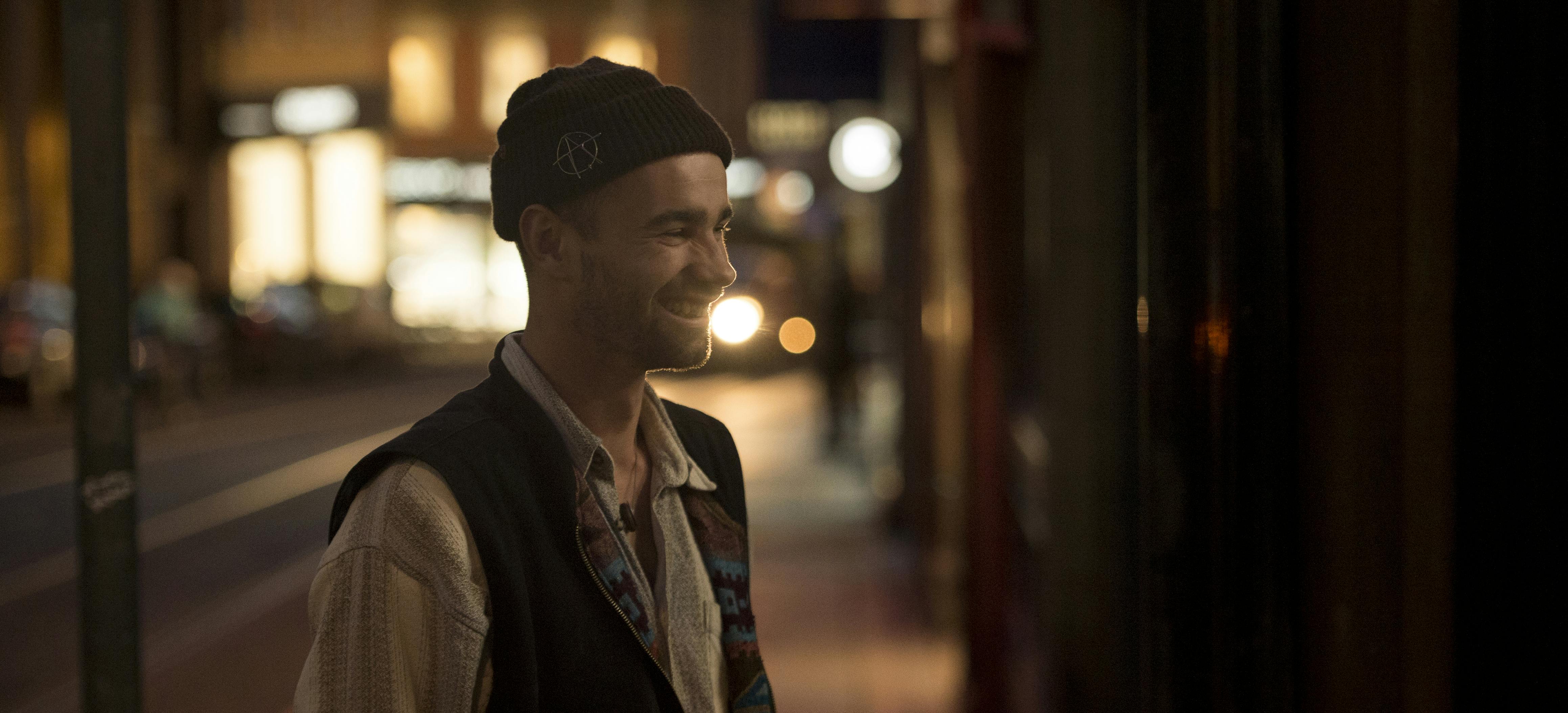 Image of Alex Hallford smiling at night with street lights in the background