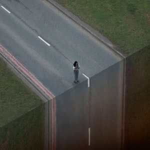 Woman on road with vertical drop