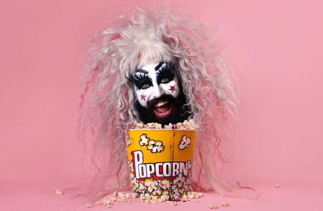 Baby Lame's head above box of popcorn with bright pink background