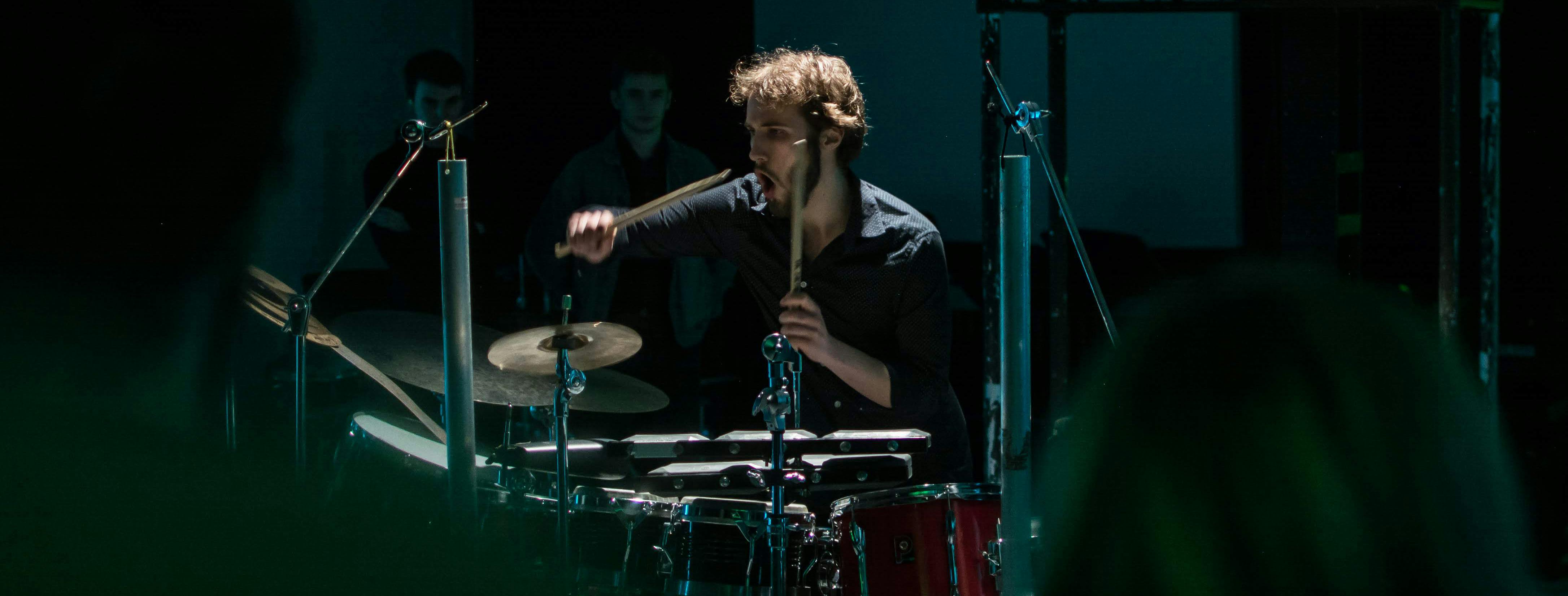BMus student Andrew Woolcock performing at Centrala. Photo Alex Henshaw. Student playing drums in dark venue