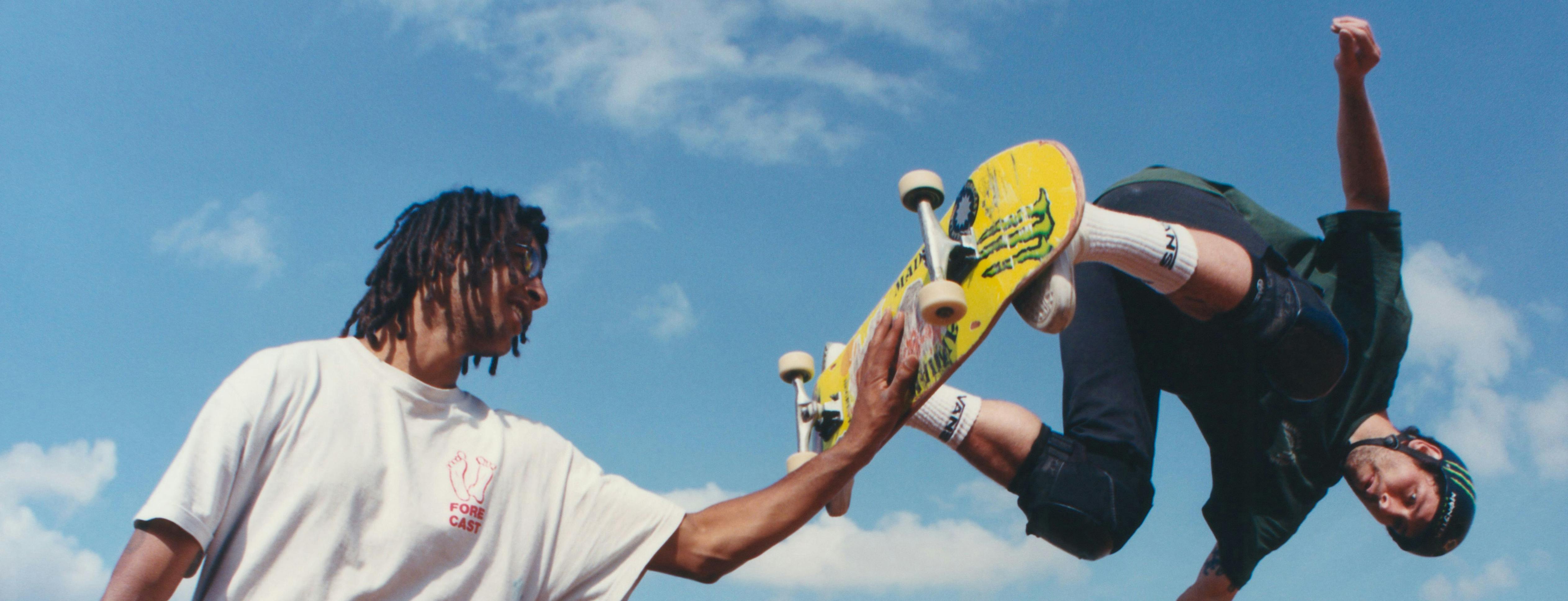 film still/image of two skateboarders on a sunny day in the midst of a trick on a half pipe