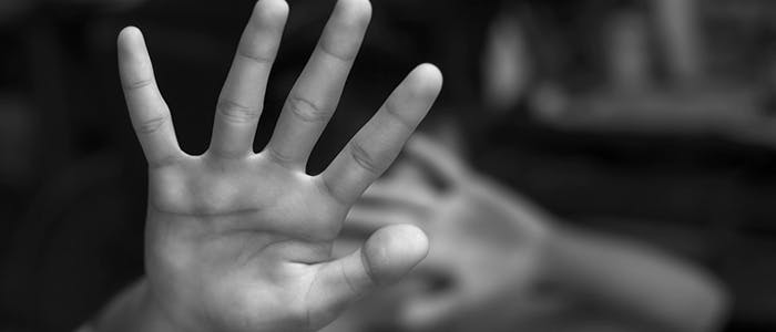 A black and white photo of a child holding up their hands to protect themselves 