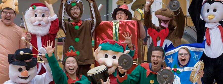 Christmas Family Shows - group of students in festive fancy dress holding instruments and smiling/laughing