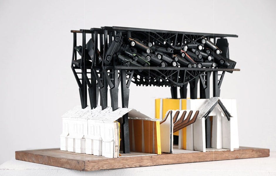 Model of buildings with black cars suspended above