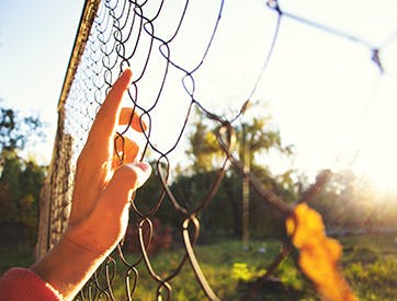 Prisoner's hand against prison fence reaching for freedom in the outside world