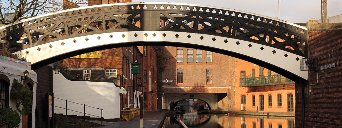 A stretch of Birmingham canal with an ornate footbridge