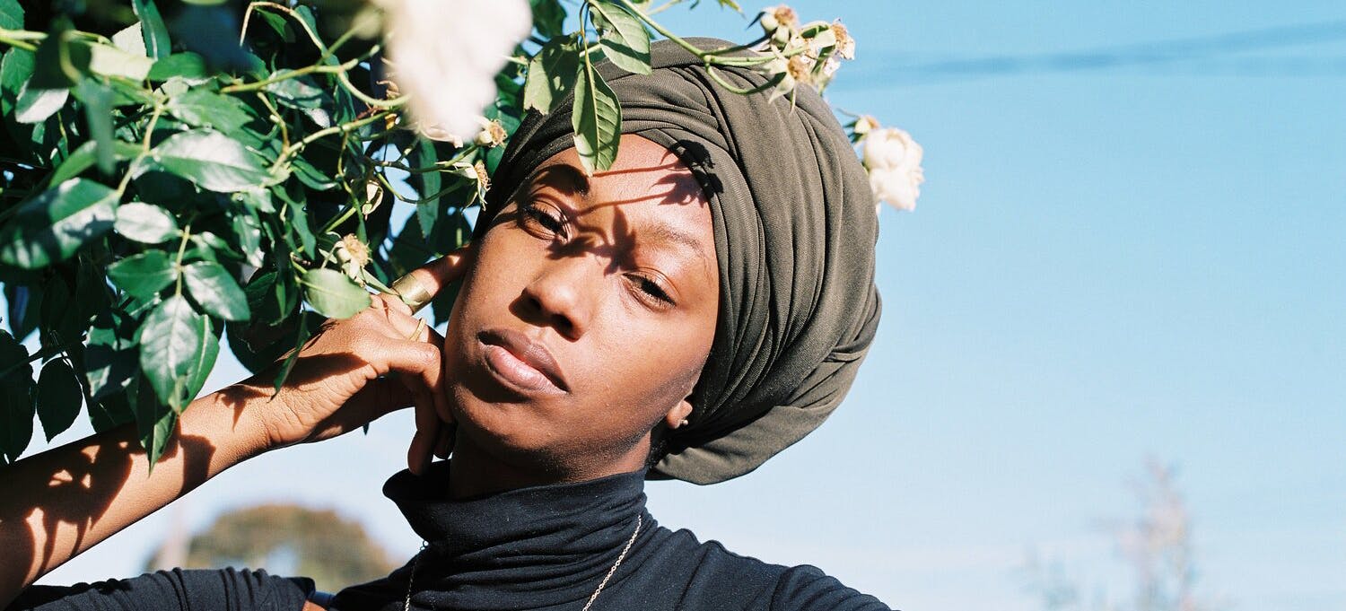 Image of Dominique outdoors on a sunny day wearing a headwrap