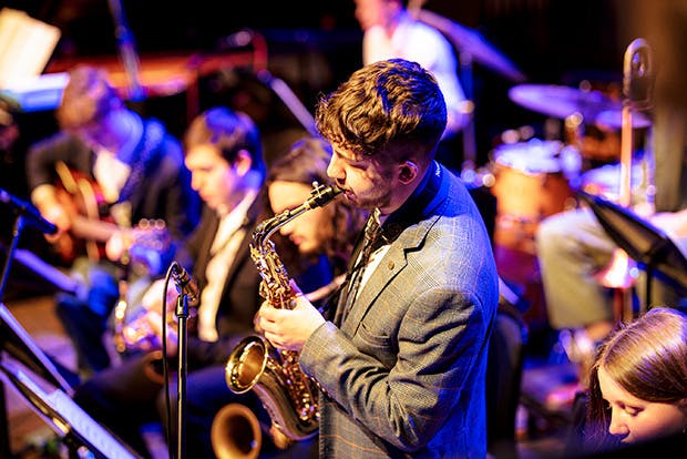 Saxophonist in foreground, band seated behind