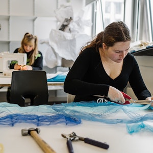 Student cutting fabric with scissors
