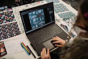 Student at laptop working on fabric design patterned with colourful mushrooms