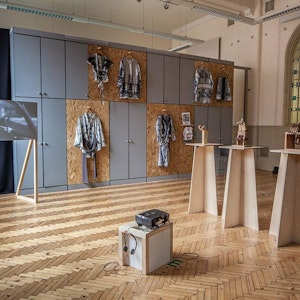 Margaret street studio with Fine Art work display, including video projected onto screen, 6 jackets hanging up on the wall at different levels and 3 wooden sculptures on stands