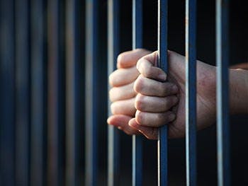 hands grasping prison bars