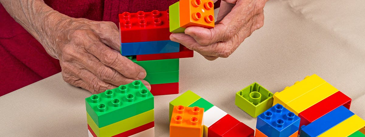 An old man playing with Lego building blocks