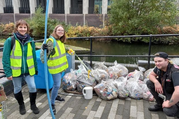 Three people around bags of litter that they have helped collect, next to the canal near University Locks