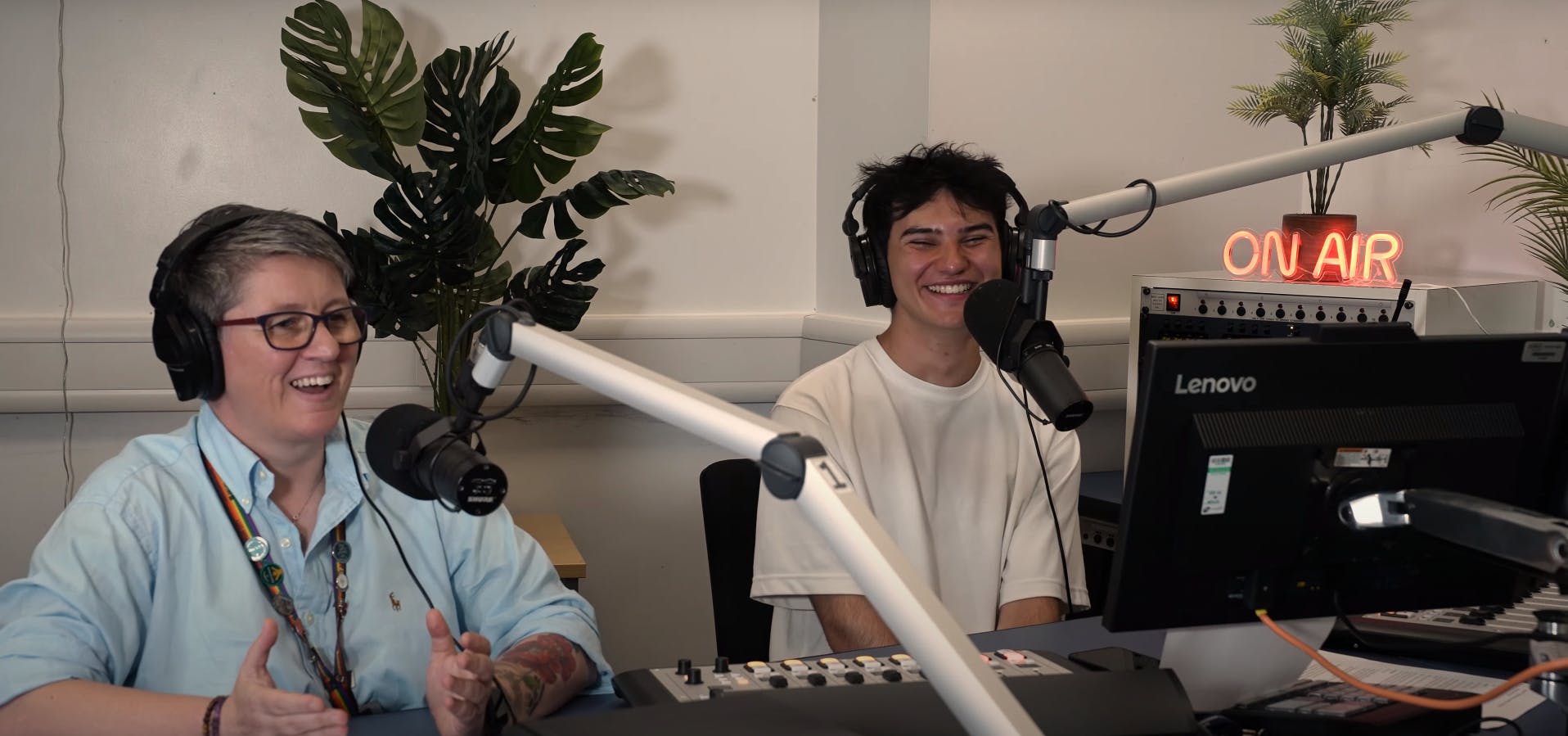 Student support advisor Lou and student Ethan host a podcast about Mental Health. They both have headphones on and are sat in front of microphones. 