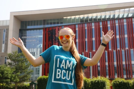 I am BCU ambassador stands in front of the Curzon building with open arms.