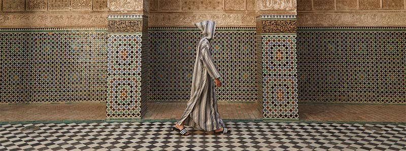Photography piece of person in tunic walking on mosaic tiles