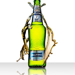 Photography piece of green beer bottle with beer surrounding the bottle