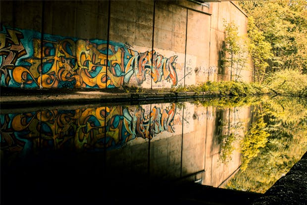 Canal under road bridge with graffiti