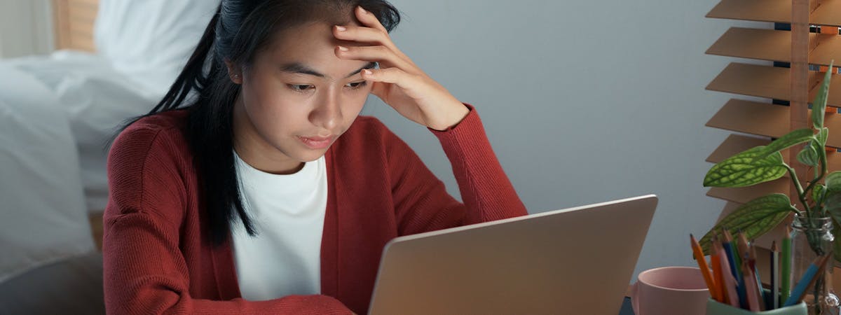 A woman at her laptop looking stressed