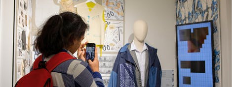 A student taking a picture on their phone of a mannikin in an exhibition