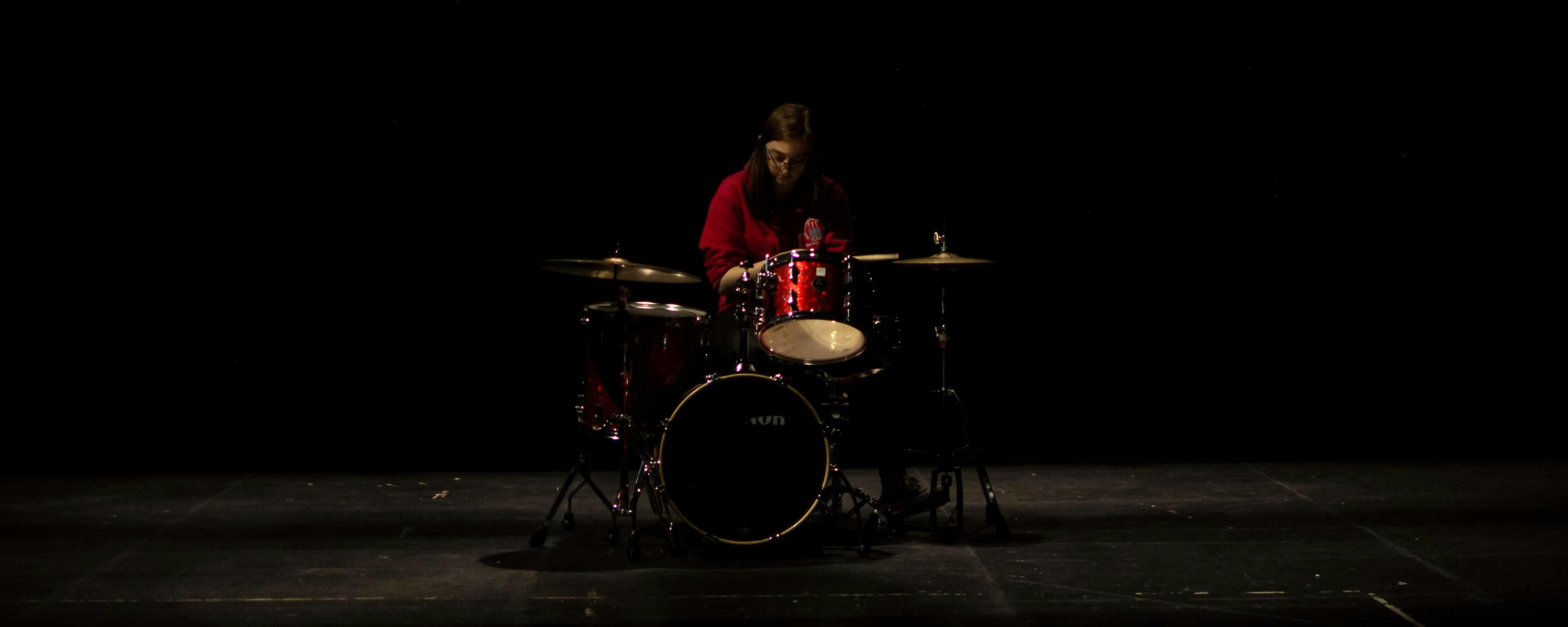 Student Cathryn Lynch playing kit in the LAB. Photo Alex Henshaw. Drummer in darkened room playing the drums