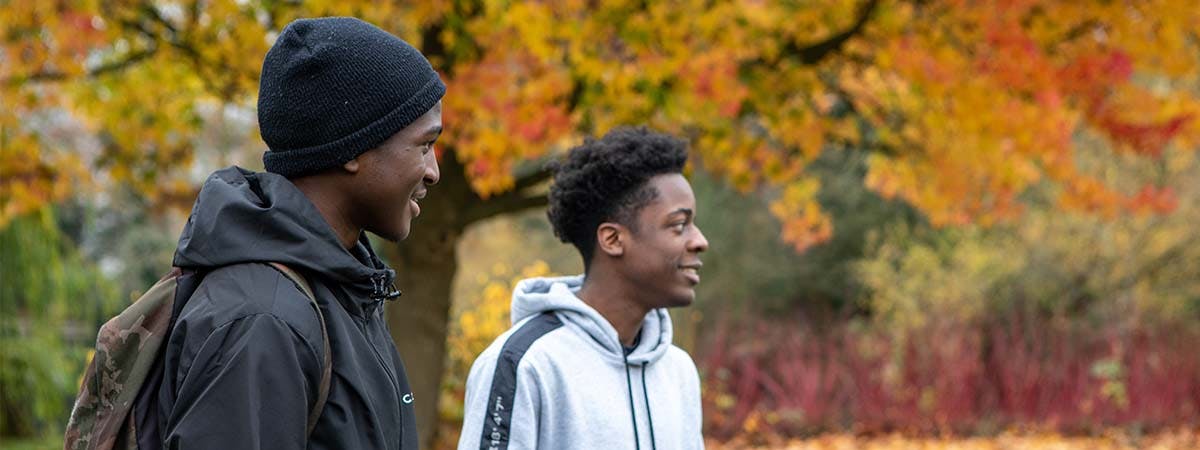 Two students in Cannon Hill park with colourful autumn leaves in the background