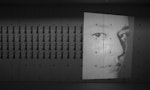 A grid of photographs of a person's face projected onto a concrete wall