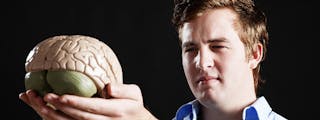 BCU Social Sciences psychology man holding a model of a human brain.
