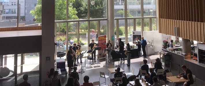 Group of Saxophone musicians playing to public in Conservatoire foyer.