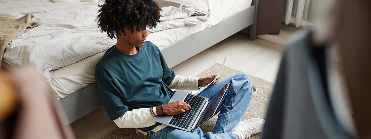 Teenage boy with afro sitting on the floor using a laptop